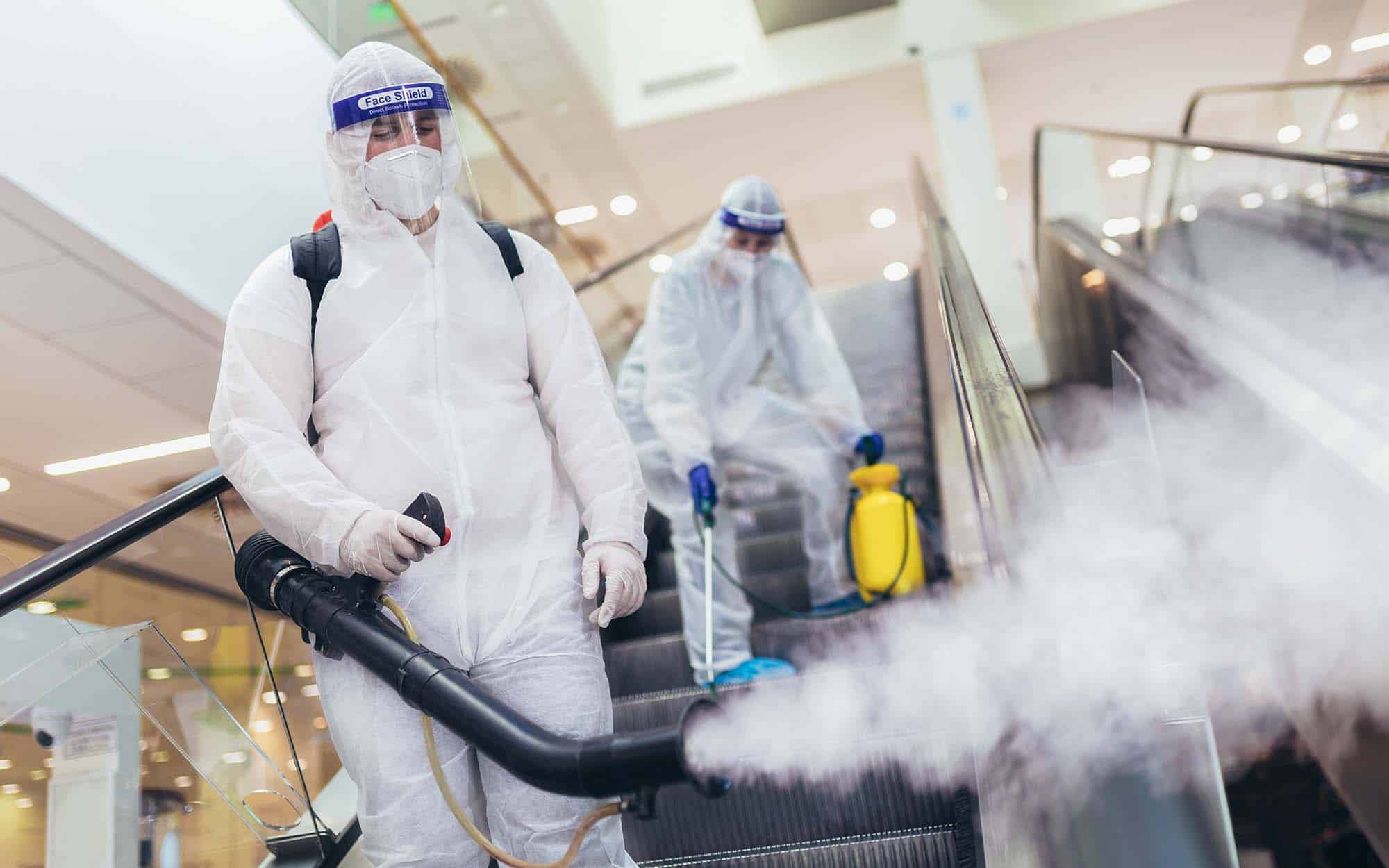 Professional workers in hazmat suits disinfecting indoor of mall, pandemic health risk, coronavirus_