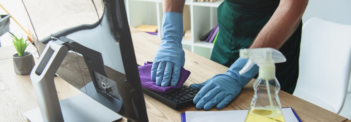 Image of a person cleaning a computer desk in the office.